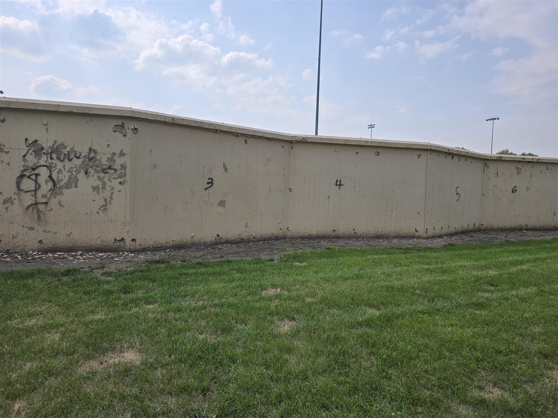 The bare, weathered concrete outfield wall before the mural